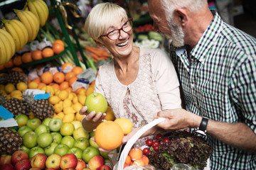 Shopping, food, sale, consumerism and people concept - happy senior couple buying fresh food
