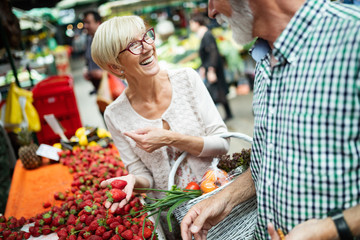 Picture of senior couple at marketplace buying vegetables