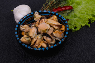Pickled mussels in the bowl served pepper, garlic and salad
