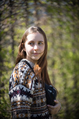 A young woman standing in green park holding a waist bag