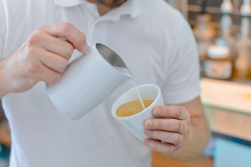 Professional barista pouring and serving cup of coffee