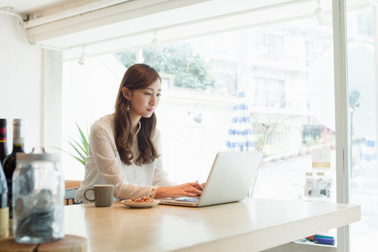 カフェでパソコンを操作する20代女性