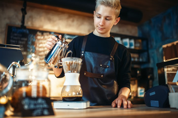 Young male barista makes latte