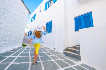 Little girl in white hat on a greek street with typical white houses