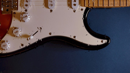 electric guitar behind the glass with water drops . color background