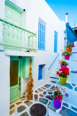 Beautiful white building's courtyard view with colorful flowerpots on stairs on the greek street