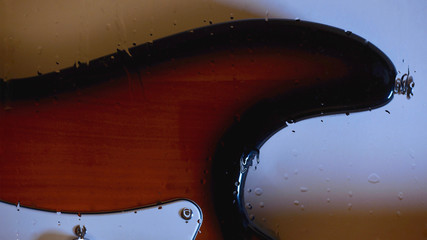 electric guitar behind the glass with water drops . color background