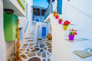 Beautiful white building's courtyard view with colorful flowerpots on stairs on the greek street