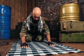 Soldier in uniform praying before terrorist attack - obrazy, fototapety, plakaty