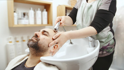 Obraz na płótnie Canvas Man at the hairdresser washing head