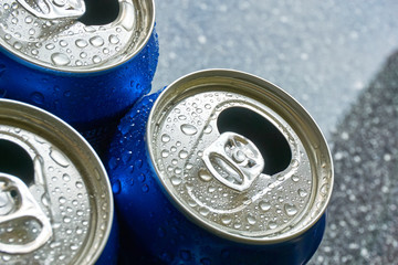 Close up of blue soda cans with open pull tab and condensation or water drops on a  grey marbled...