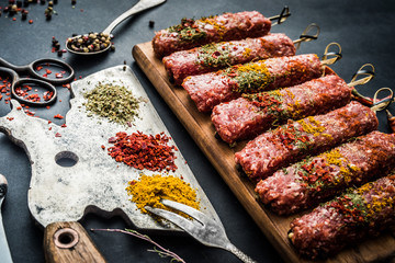 Raw kebab with spices and old kitchen ax on a black table