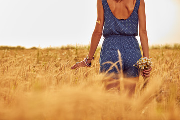 Naklejka na ściany i meble Woman with bouquet of flowers in a wheat field.