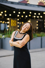 A woman with dark hair, middle-aged, closed her eyes and smiles, hugging herself with her hands. The concept of peace, happiness and tranquility in the soul