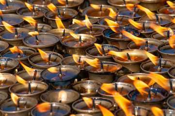 Many oil candles burning at temple interior