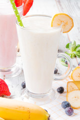Fresh milk, strawberry, banana on wooden table, assorted protein cocktails with fresh fruits. Natural background.