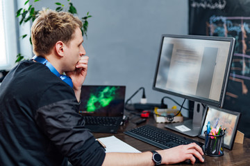 Serious young man concentrated on problem on the PC screen. Smart programmer is working hard in It company indoors.