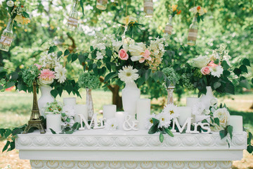The phrase "Mr & Mrs" in a wedding decor on a white fireplace surrounded by vases of flowers