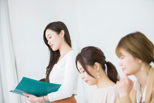 ファイルを持ち発表する20代女性