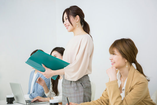 ファイルを持ち発表する20代女性