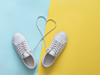 white sneakers with laces in heart shape. Fashion Trendy Trainers with Heart. Love, Hipster Set. Female sneakers, sport shoes in flat lay style, top view. Fitness, active lifestyle, body care concept