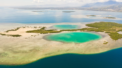 Tropical island with mangroves and turquoise lagoons on a coral reef, top view. Fraser Island, seascape Honda Bay, Philippines. Atolls with lagoons and white sand.