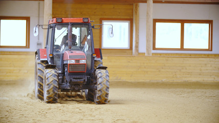 Tractor driving inside the horse riding arena