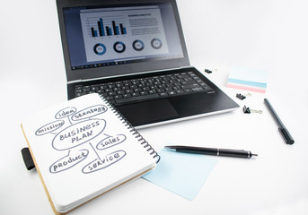 Minimalistic workplace concept, with a laptop, pen and business work records on a white background. Image of business plan, startup. Close up image