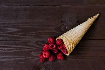 Fresh organic homemade garden raspberry in a waffle cone, ice cream cone on a brown background. Copy left view - Powered by Adobe