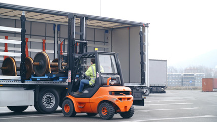 Forklift loading train wheels on huge truck trailer