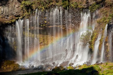 糸のような水の流れのある滝と虹