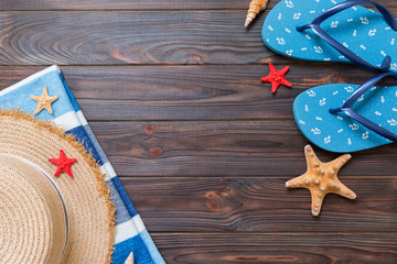 Straw hat, blue flip flops, towel and starfish On a dark wooden background. top view summer holiday concept with copy space