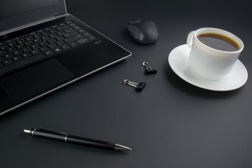 Minimalistic workplace concept, with a laptop, pen and business work records on a dark background....