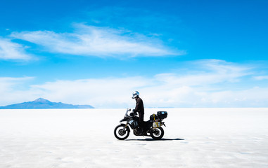 Fototapeta premium Tourist with equipment riding on motorbike in sunshine Salar de Uyuni