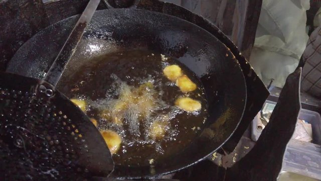 Close-up frying of Pakora, or pakoda, pakodi, fakkura, bhajiya, bhajji, bhaji or ponako, a fried snack fritters made with gram flour, of Indian subcontinent. slow motion Handheld stabilized gimbal 4k