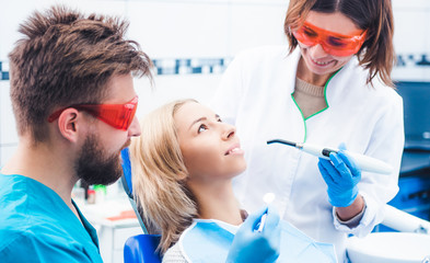 Dentists in red glasses lighting dental seal with ultraviolet lamp