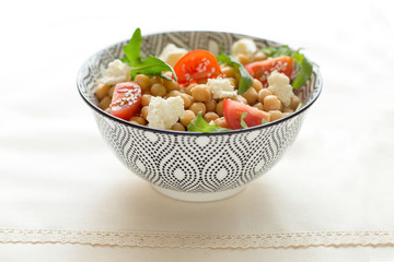 Fresh organic salad with chickpeas, arugula, tomatoes, rustick table, close up