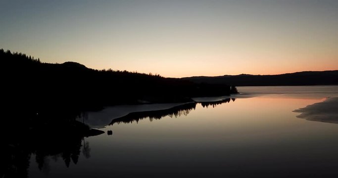 Drone footage over the lake Snaasavatnet in Norway - Scandinavia. The Lake is partly frozen in april. After sunset.