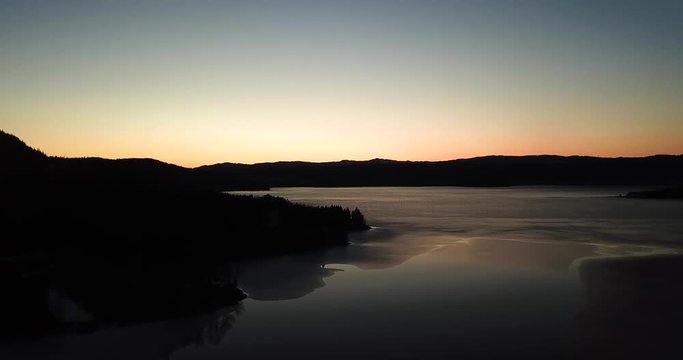 Drone footage over the lake Snaasavatnet in Norway - Scandinavia. The Lake is partly frozen in april. After sunset.