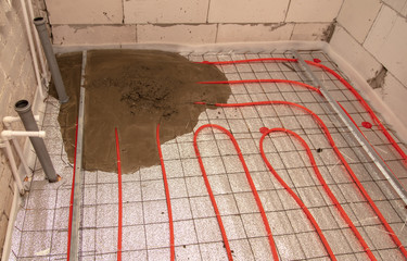 A worker pours concrete underfloor heating in the room