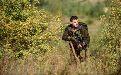 Fototapeta premium Man wear camouflage clothes nature background. Hunting permit. Hunting is brutal masculine hobby. Hunting equipment for professionals. Bearded serious hunter spend leisure hunting. Hunter hold rifle