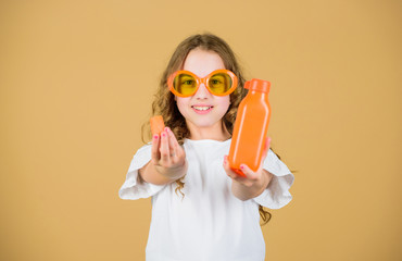 Vitamin nutrition. Fashion kid sunglasses drink refreshing vitamin juice. Health care. Summer vitamin diet. Happy childhood. Natural vitamin source. Girl eat carrot vegetable and drink carrot juice