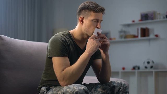 Sad male soldier kissing family photo, missing wife and children, loneliness