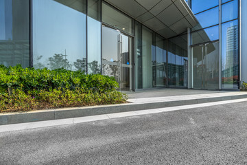 empty asphalt road near glass office building.