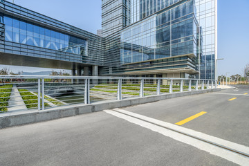 empty asphalt road near glass office building.