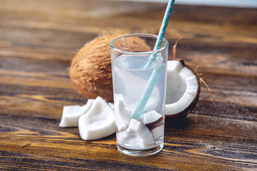 Coconut water in the composition with white flesh on wooden background. Organic product widely used in cosmetology