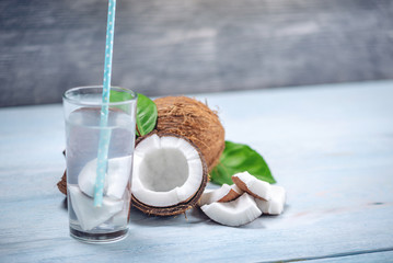 Coconut water in the composition with white flesh on blue wooden background. Organic product widely used in cosmetology