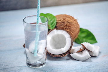 Coconut water in the composition with white flesh on blue wooden background. Organic product widely used in cosmetology