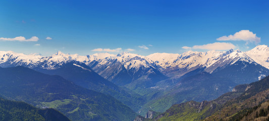 panoramic view on snowy peak mountains under blue sky