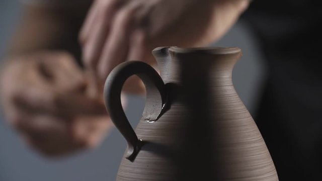 Close up of Potter's hands making jug handle from clay. Potter's work. Man hands making clay product. Step by step